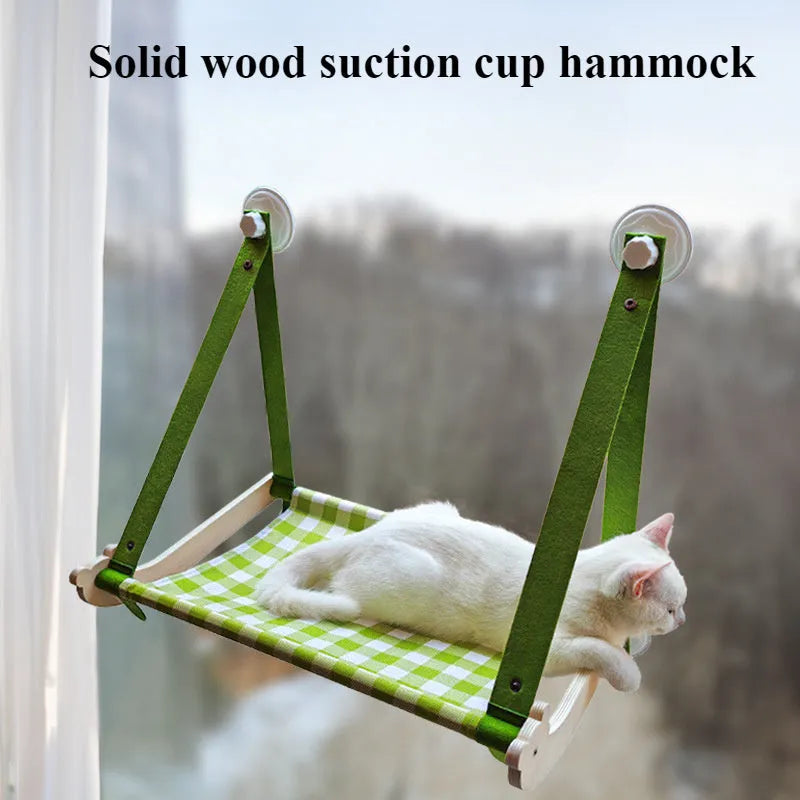 Pink cat hammock with wooden frame and suction cups attached to a window, with a cat resting inside.