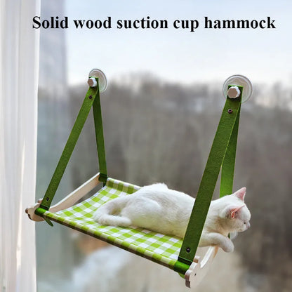 Pink cat hammock with wooden frame and suction cups attached to a window, with a cat resting inside.