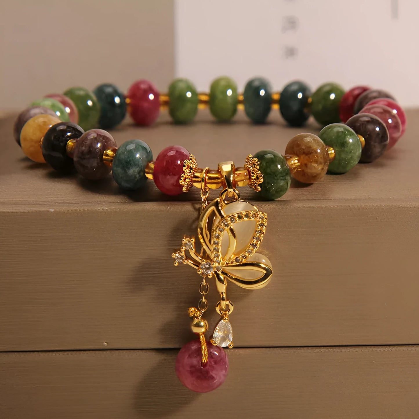 Colourful women's bracelet with butterfly charm, beads, and tourmaline accents on an alloy chain.