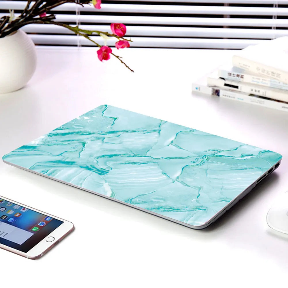 Plastic MacBook protective case in a marble pattern colour, shown next to a compatible Apple laptop.
