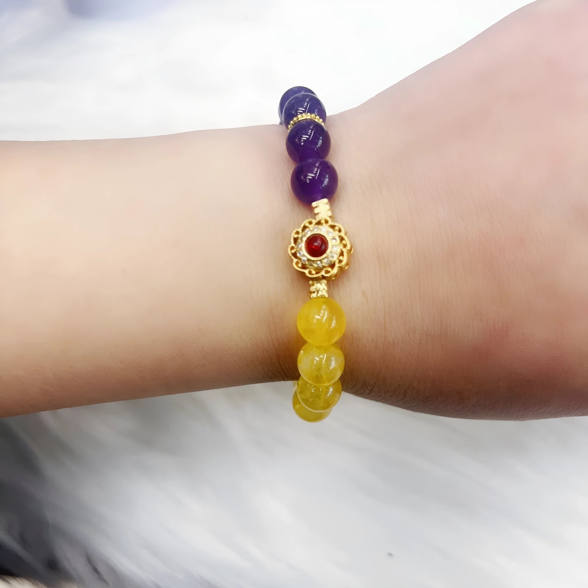 Handmade women's crystal bracelet in yellow and purple colours on a wrist.