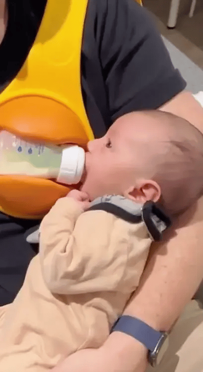 A yellow hands-free baby bottle holder that allows parents to multitask during feeding time