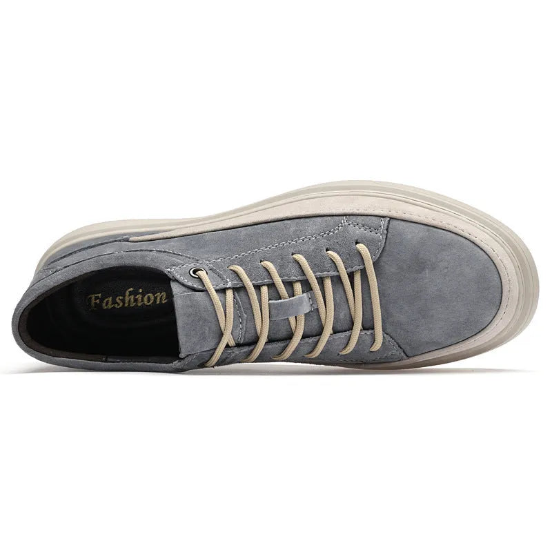 Men's grey low-top casual leather skate shoes with round toe and flat rubber sole on a wooden surface.