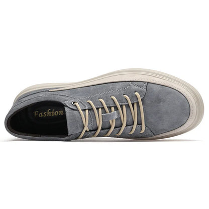 Men's grey low-top casual leather skate shoes with round toe and flat rubber sole on a wooden surface.