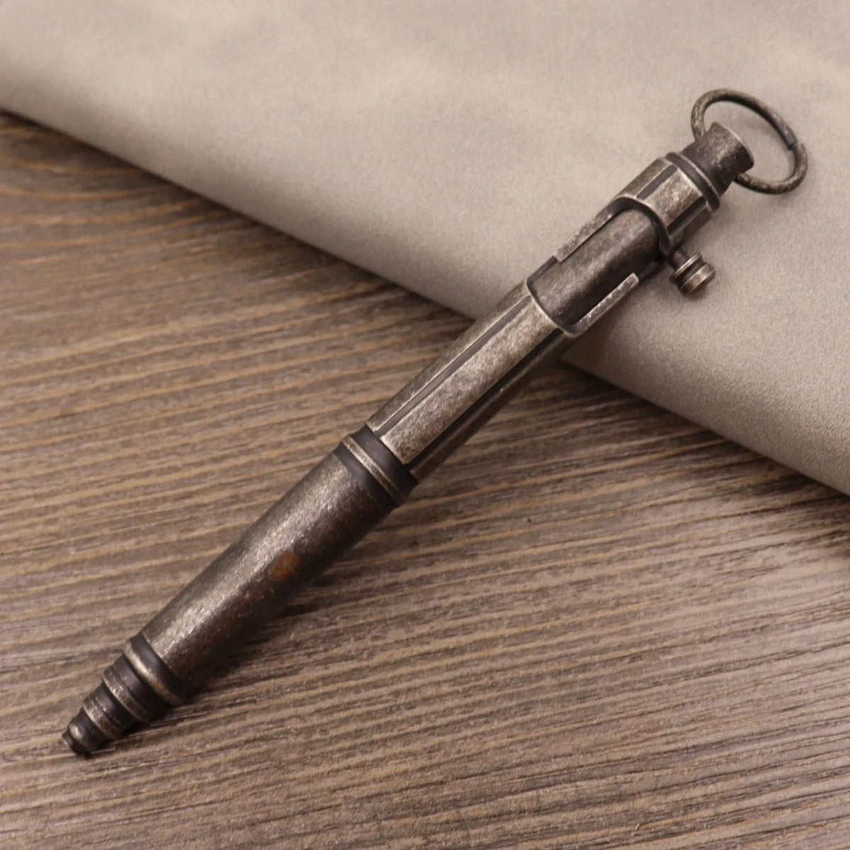 Brass tactical pen with press bolt mechanism showing cylindrical design and six ring details