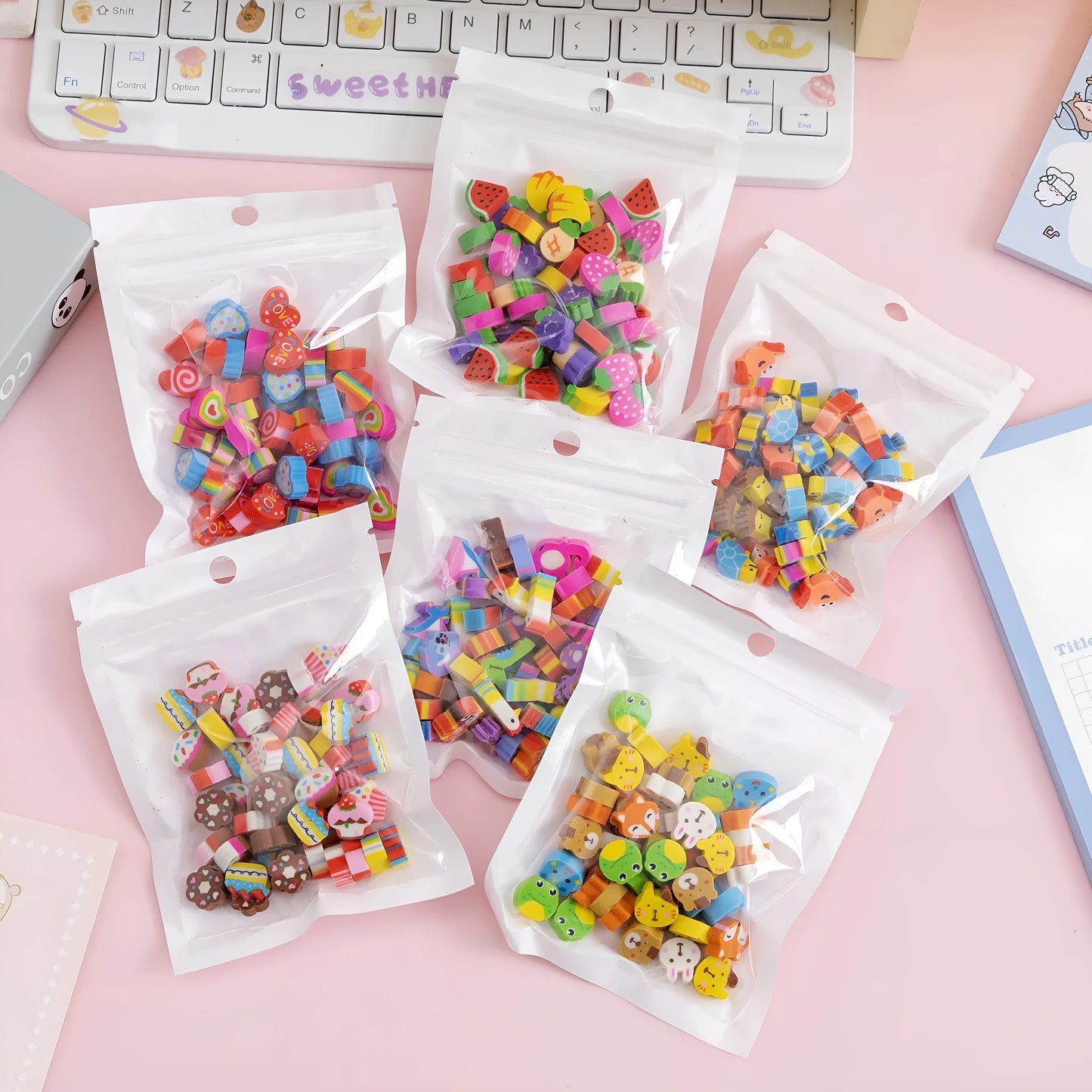 Assortment of 50 small cartoon erasers in pearlescent bags, showing fruit, animal, and holiday designs.
