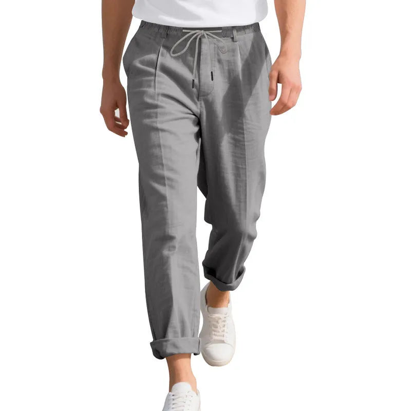Men's light beige linen trousers with a loose straight leg and drawstring waist on a hanger.
