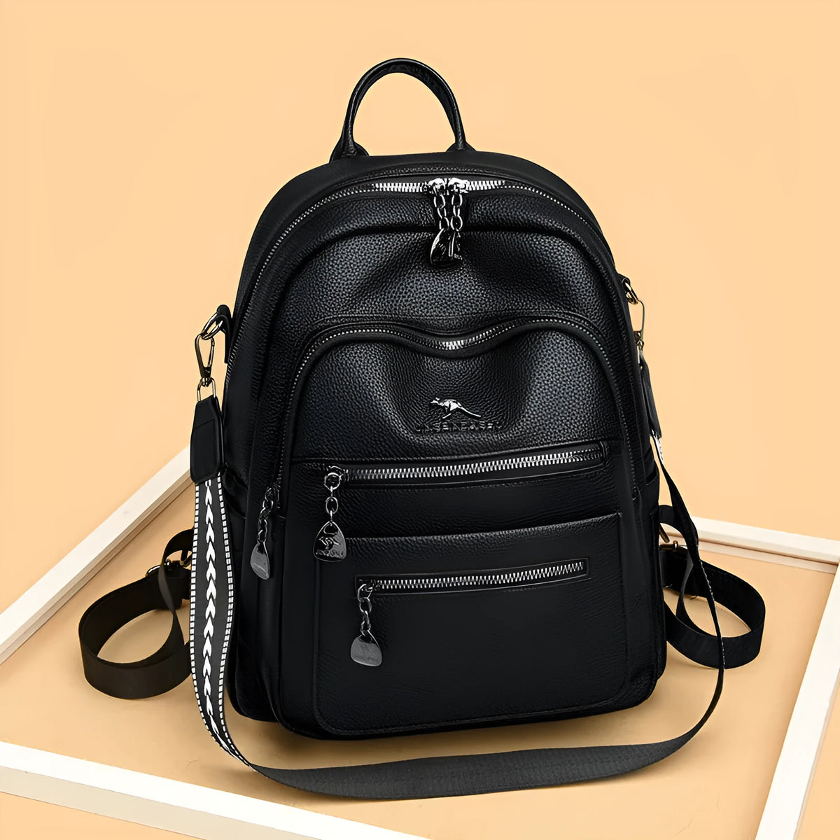 Genuine leather multi-functional commuting backpack with flap pocket, polyester lining, and metal letter patchwork details in black.