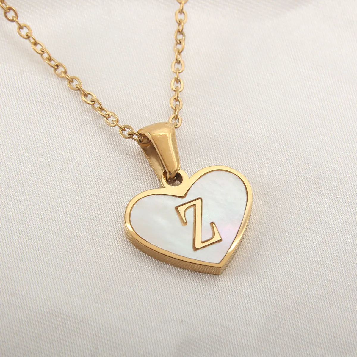 Gold-plated clavicle necklace with a white shell heart pendant, personalised with a letter from A to Z.