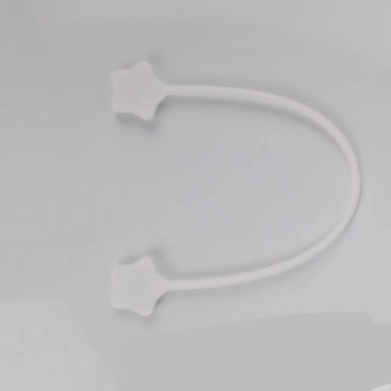 Compact purple silicone cable winder with magnet, shown coiling a white headphone cable.