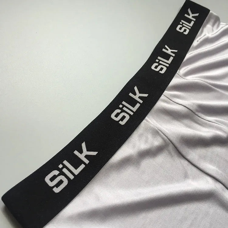 Men's loose-fitting silk shorts in navy blue on a neutral background.
