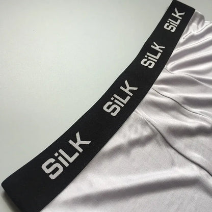 Men's loose-fitting silk shorts in navy blue on a neutral background.