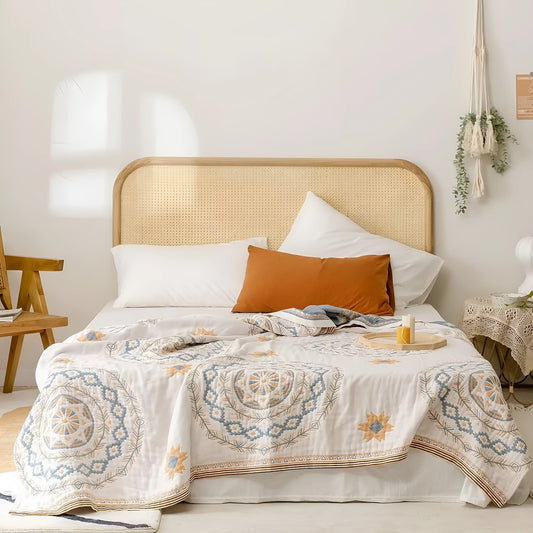 Close-up of a beige cotton waffle weave blanket with a subtle geometric pattern, showing its textured honeycomb surface.