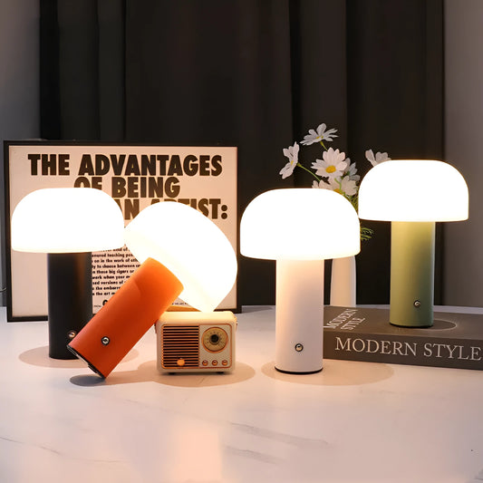 Compact white USB table lamp with integrated UK plug and a charging cable on a wooden desk.
