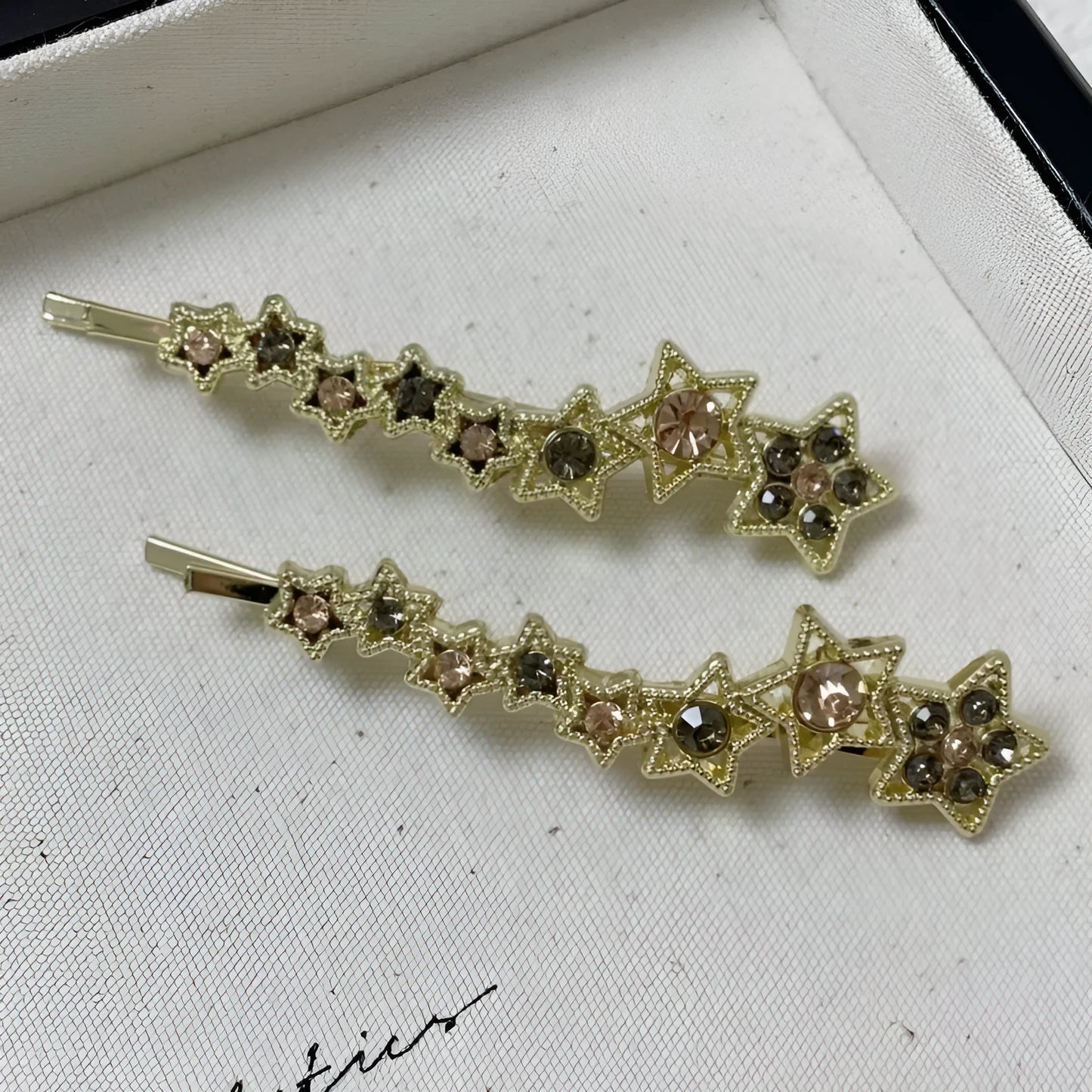 Gold electroplated hair barrette with a rhinestone five-pointed star, broken clip style for bangs.