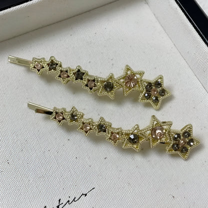 Gold electroplated hair barrette with a rhinestone five-pointed star, broken clip style for bangs.