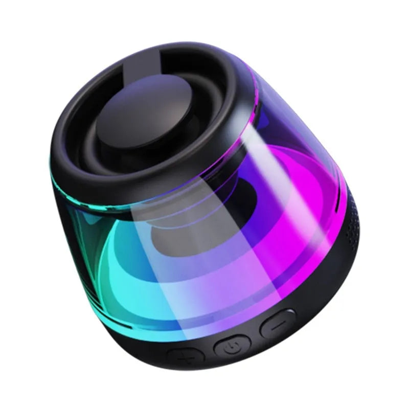Small white portable Bluetooth speaker with LED light glow on a wooden desk next to a smartphone.