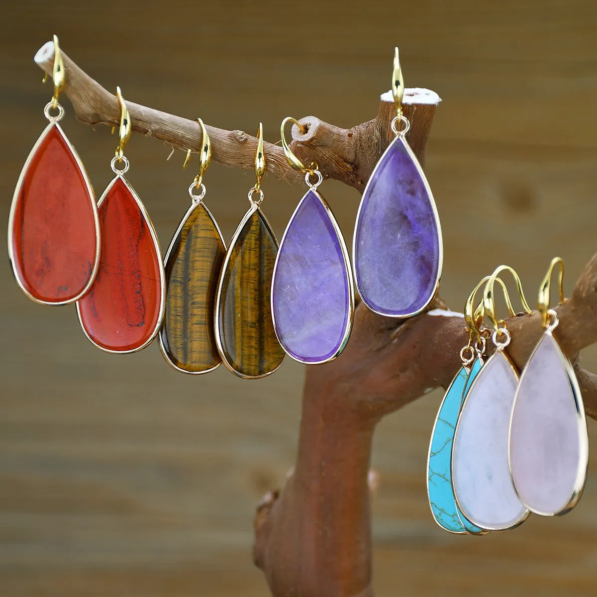 Close-up of long, polished tigereye stone drop earrings with a fishhook clasp on a neutral background.