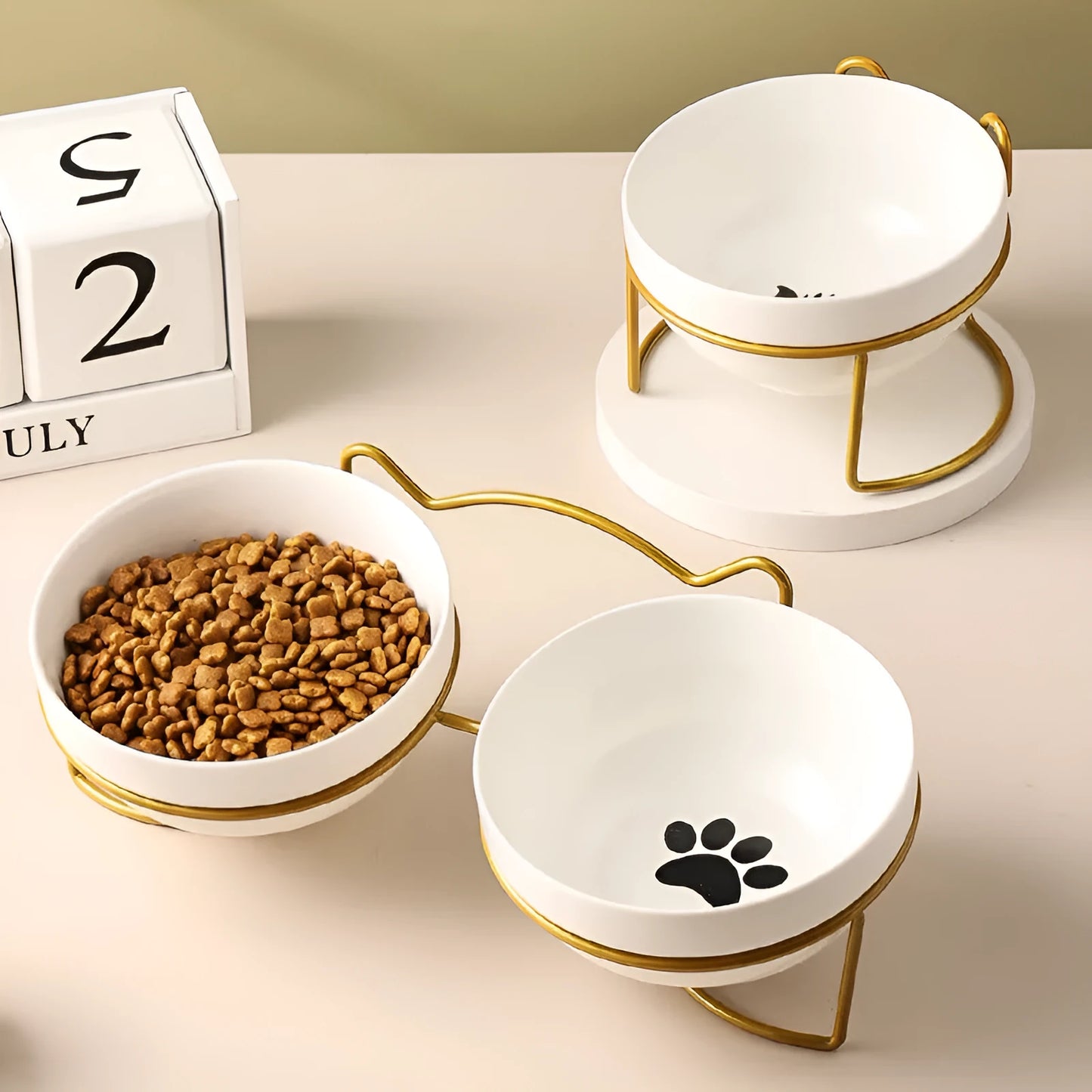 White ceramic pet bowl with cat paw design on a black iron frame raised feeder.