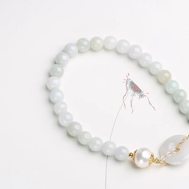 A geometric jade and pearl bracelet for women with a hand-finished peace buckle pendant.