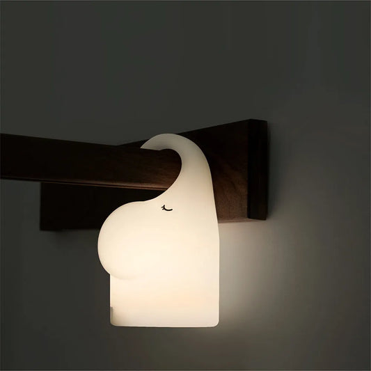 DOMI Elephant-shaped silicone night light with warm white LED glow, shown on a bedside table.