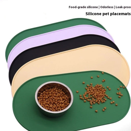 Green silicone cat feeding placemat with raised edges on wooden floor containing water bowl
