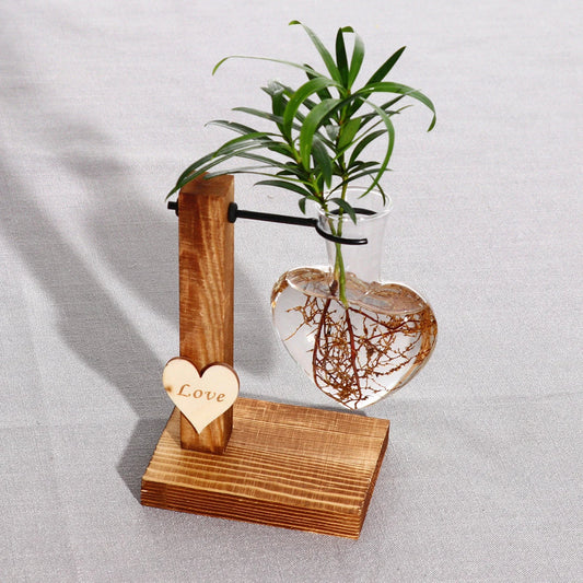 Elegant heart-shaped glass terrarium with wooden stand, showcasing a natural, minimalist design perfect for indoor plant display or decorative accents.