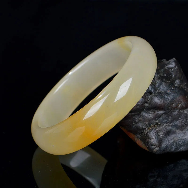 A polished natural light jade bracelet in a traditional Chinese style, shown on a wrist.