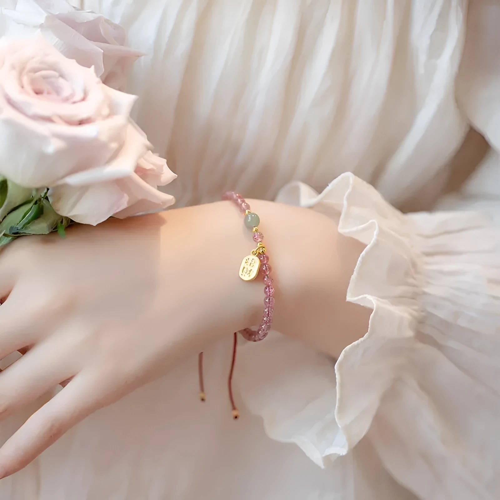 A hand-woven red rope bracelet with a strawberry quartz or garnet crystal, shown in simple styling.
