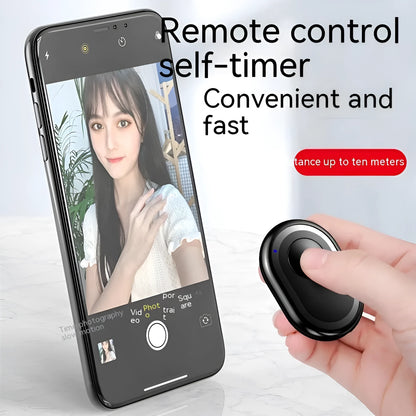 Small black wireless Bluetooth remote control for smartphone camera with self-timer function.