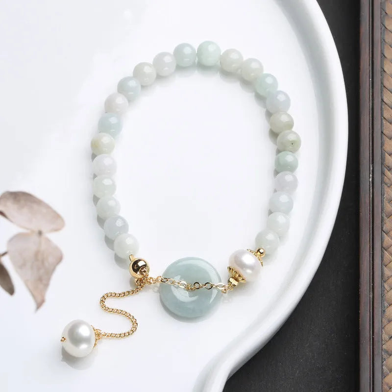 A geometric jade and pearl bracelet for women with a hand-finished peace buckle pendant.