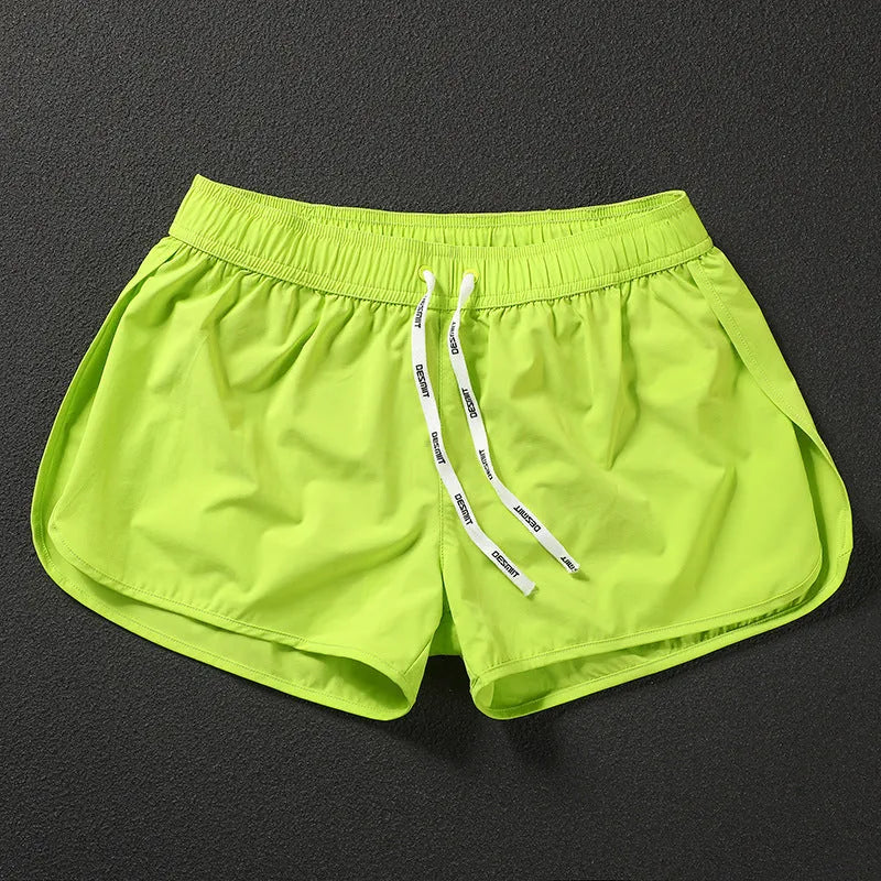 Men's loose orange beach shorts with elastic waist on a sandy shore