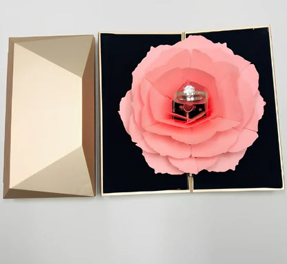 Rotating ring box with embossed paper exterior showing 360-degree mechanism and flannel interior