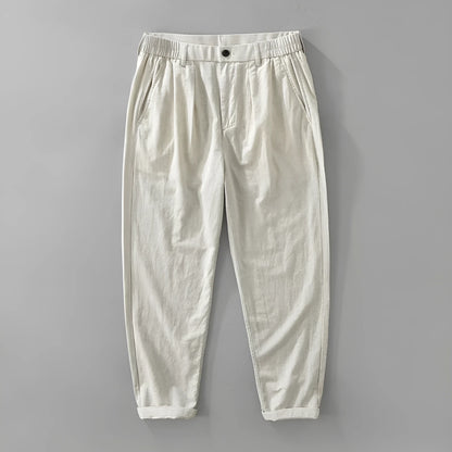 Man wearing loose beige straight-leg cotton linen trousers in a casual setting