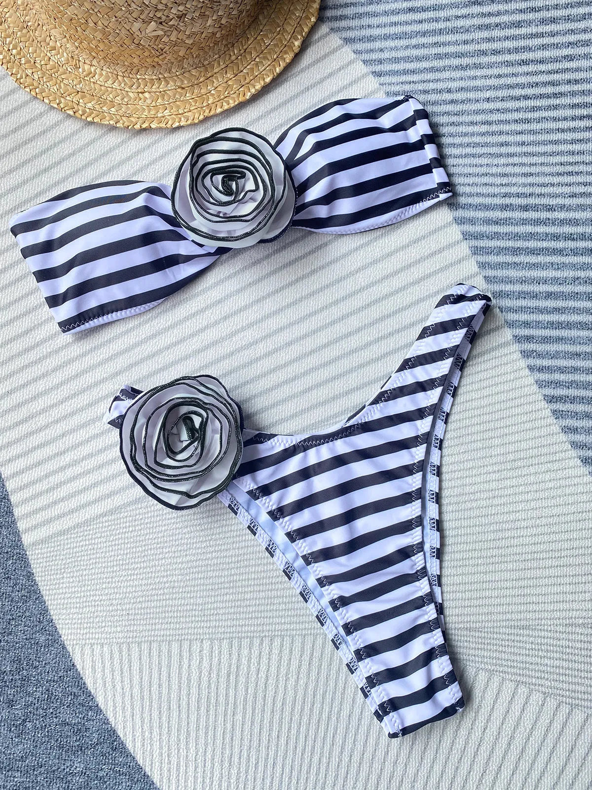 Women's black bikini set with side split bottoms and a white three-dimensional flower detail on the top.