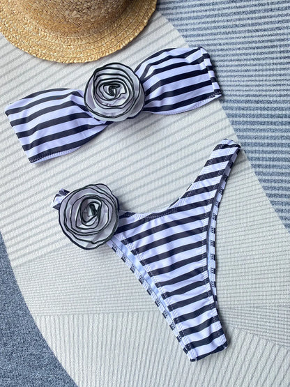 Women's black bikini set with side split bottoms and a white three-dimensional flower detail on the top.