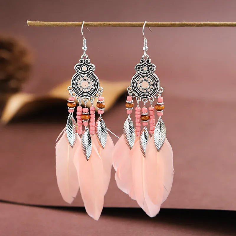 Bohemian feather leaf pattern alloy earrings in round drop shape on a colour selection background.