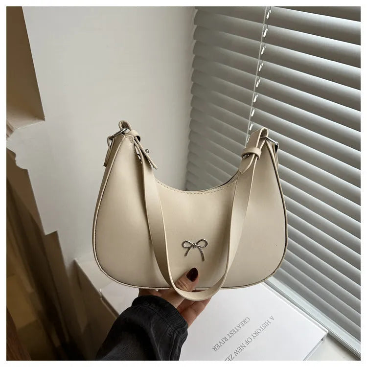 Women's silver dumpling-shaped PU crossbody bag showing front sandwich pocket and single shoulder strap.