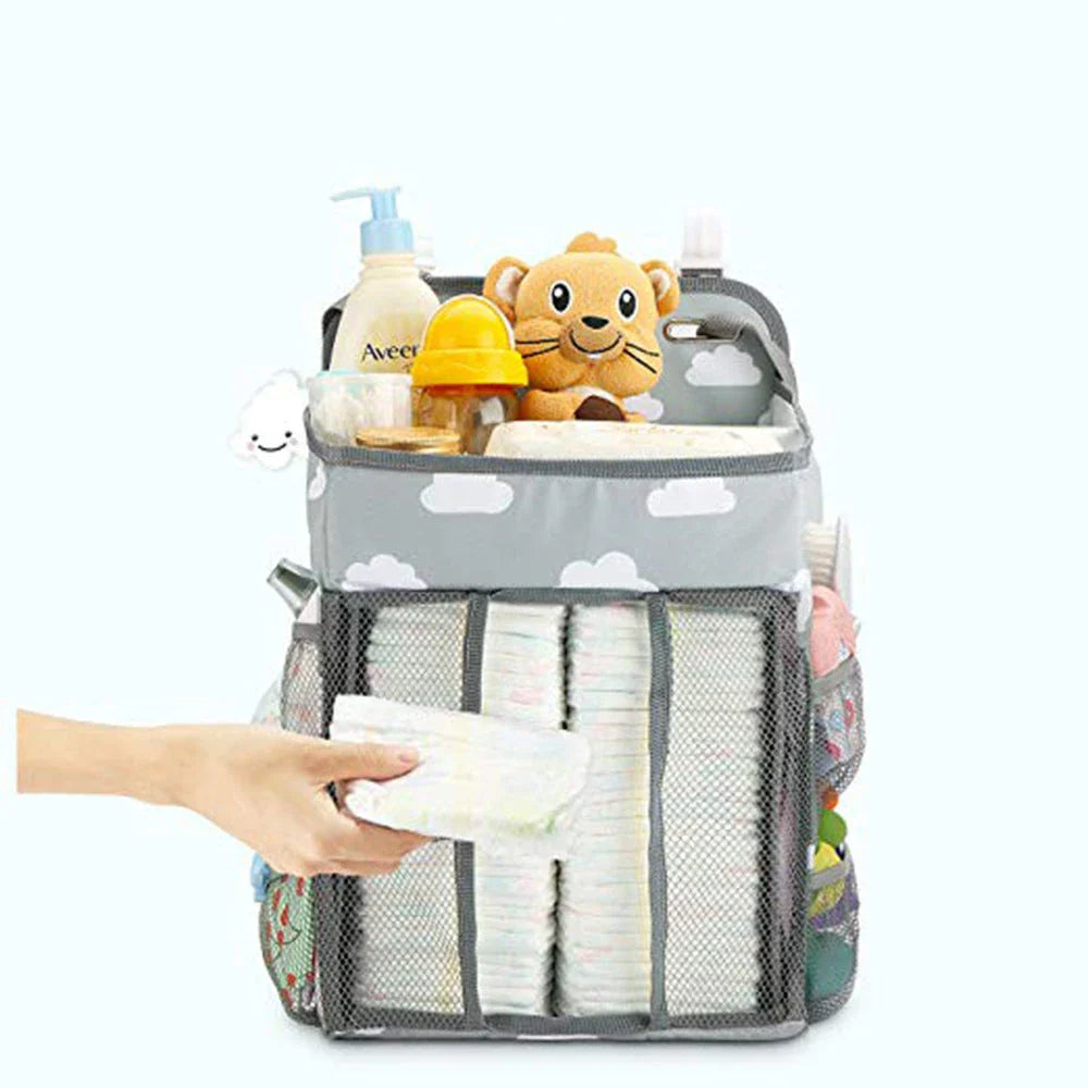 Portable baby crib organizer with hanging storage pockets for diapers, bottles, toys, and other nursery essentials