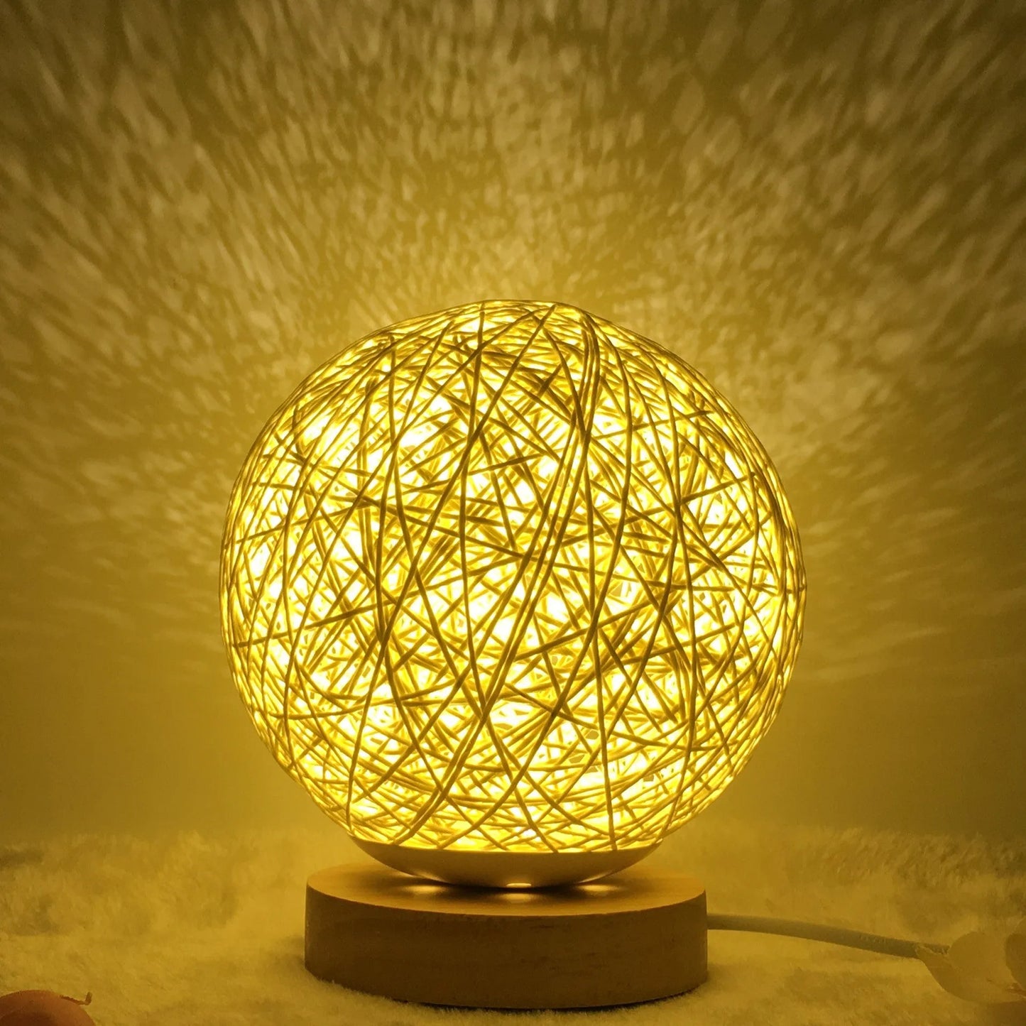 Spherical hand-knitted rattan table lamp with remote control on a wooden desk