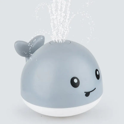 Automatic water-spraying whale bath toy with colourful lights floating in bath water.
