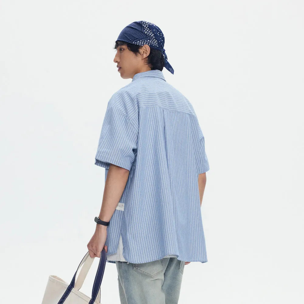 Blue and white striped loose-fitting short-sleeved overalls shirt on a hanger.