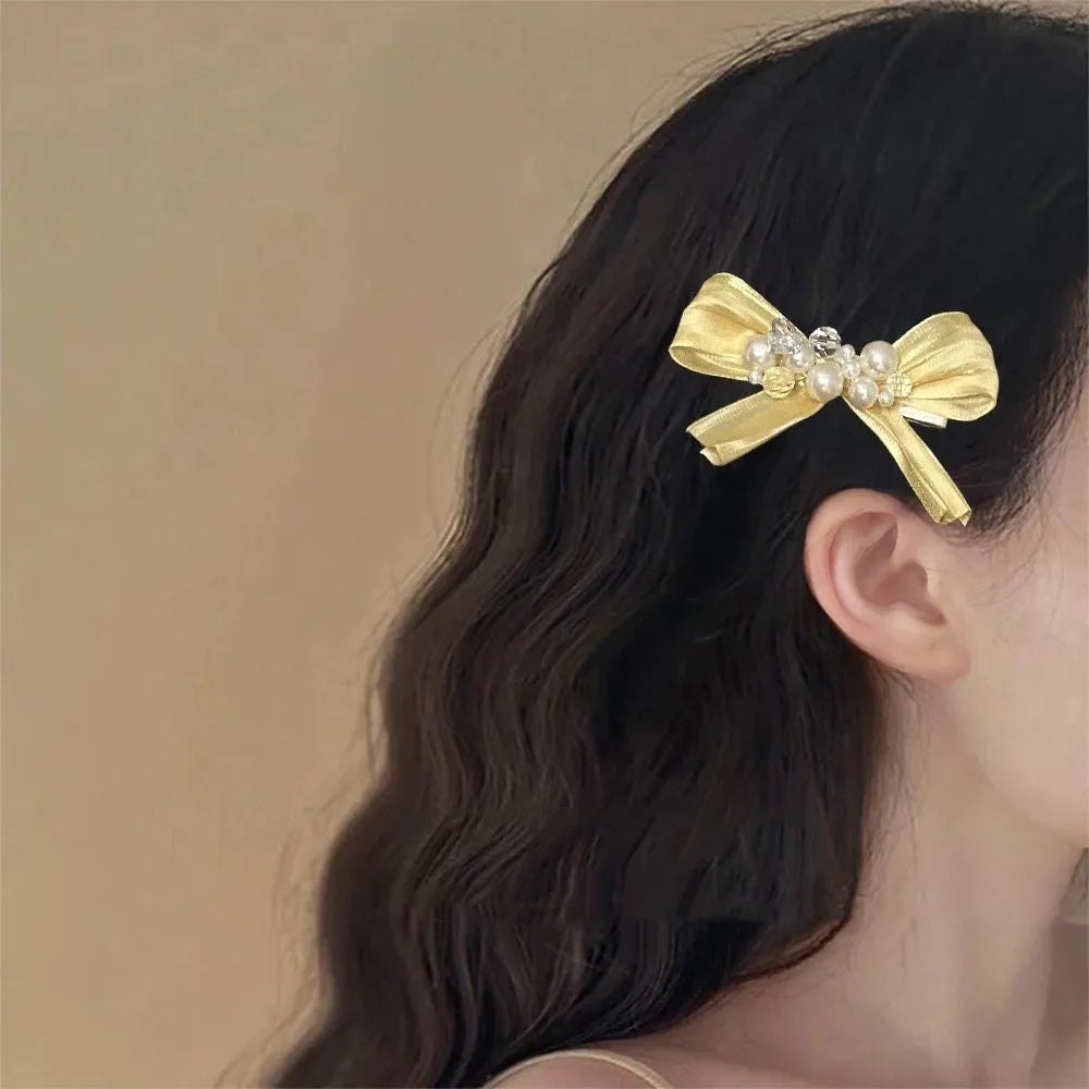 Yellow bow hair barrette clip with rhinestone pearl detail on duckbill clip base