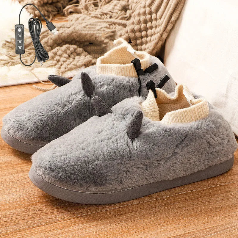 USB heated slippers in grey with a USB cable plugged into a power bank, showing the enclosed velvet design.