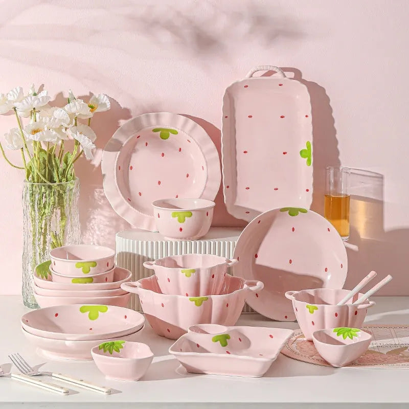 Porcelain dinnerware set with strawberry pattern, showing plates, bowls, and a twist spoon in various sizes