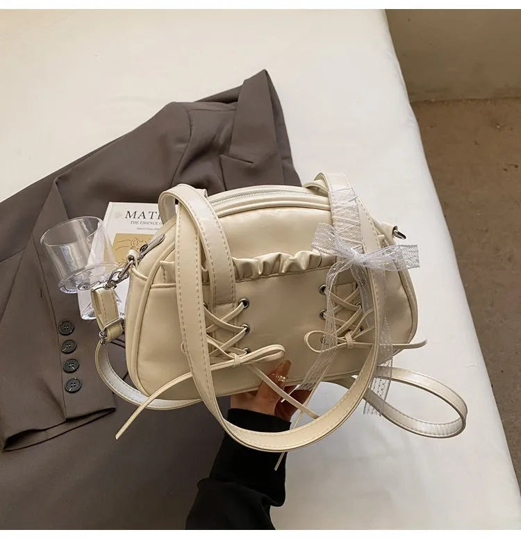 Milky white women's shoulder handbag with a large bandage bow and visible stitching, showing the internal phone pocket.