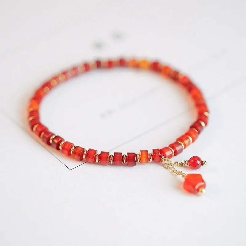 Hand-woven red agate beads bracelet with lucky charm in ethnic style, showing diamond-shaped beads.