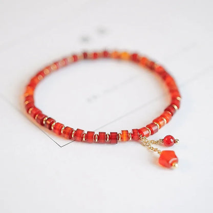 Hand-woven red agate beads bracelet with lucky charm in ethnic style, showing diamond-shaped beads.