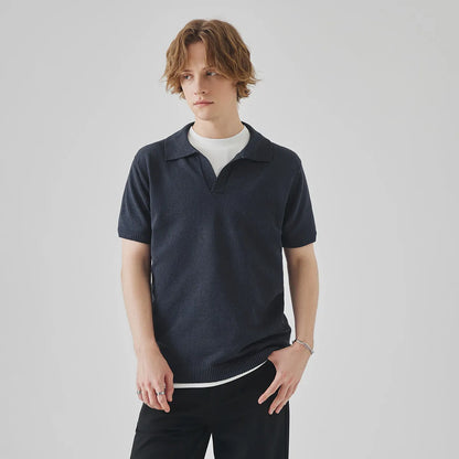 A man's solid-colour knitted polo t-shirt with short sleeves and a collar, shown in navy blue.