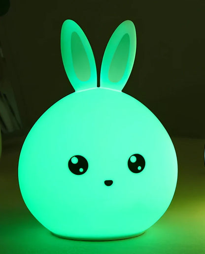 White silicone rabbit night light with USB charging cable showing touch sensor area and colourful LED illumination